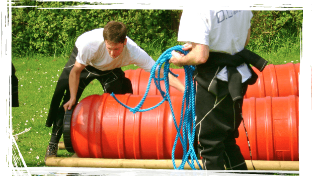 Two persons building a raft as part of their team activity.