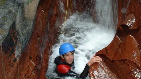 A person on a waterfall while on a canyoning activity holiday in France.