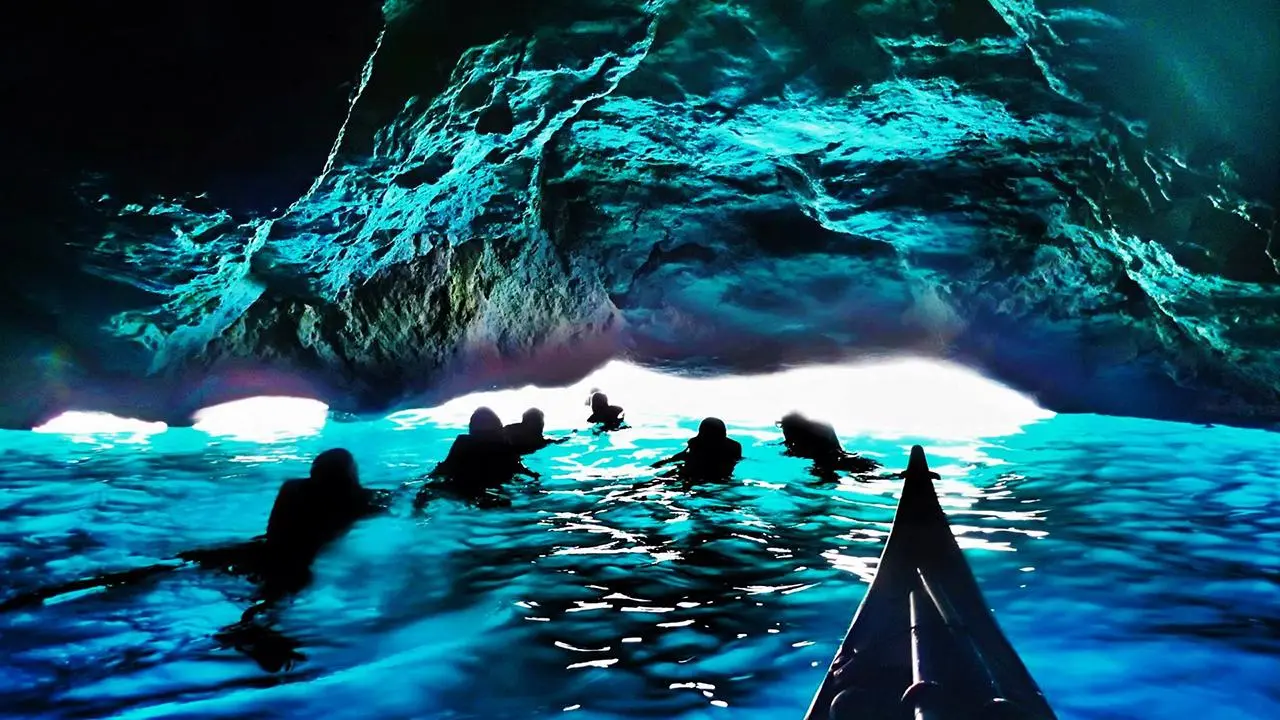 People swimming under a cave