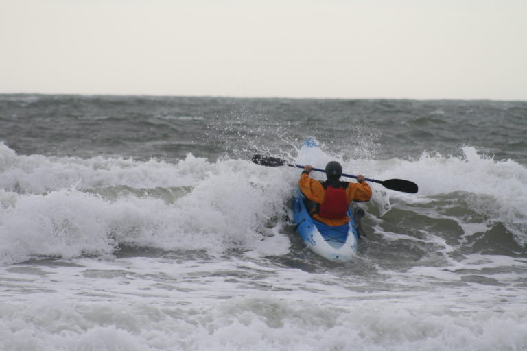 A person doing surf kayaking in the sea.
