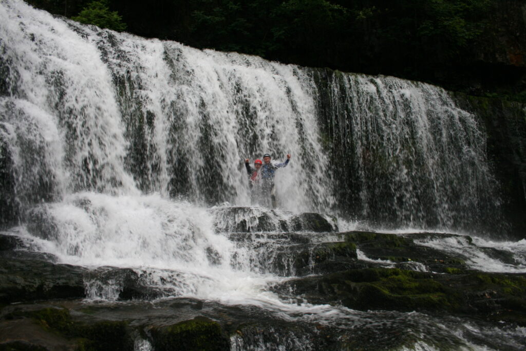 people in their gorge walking adventure passing by a waterfall