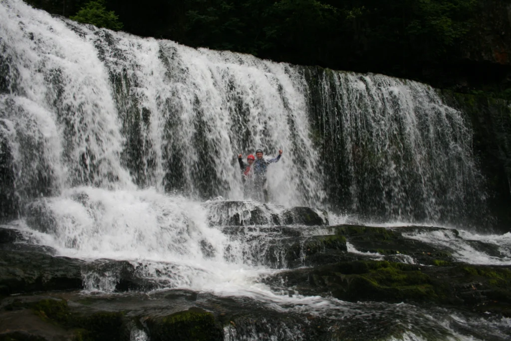 people in their gorge walking adventure passing by a waterfall