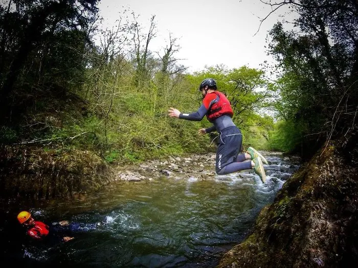 A person jumping on the water during coasteering activity in Wales