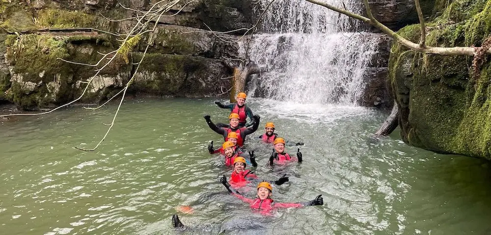 Group of people in a waterfall during their activity weekend in Wales.