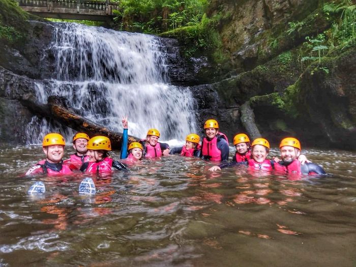 group in a lake swimming near a waterfall