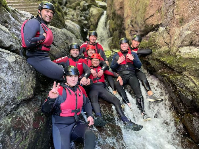 group of men sat on a rock with flowing water