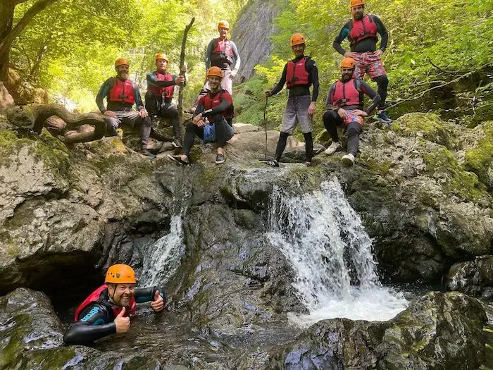 Group of people in a small waterfall during their gorge walking team building activity.