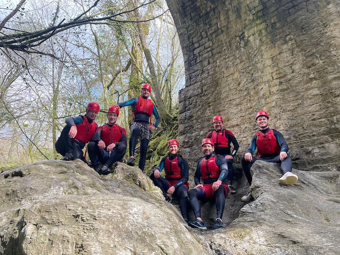 group of people in gorge walking kit under a bridge