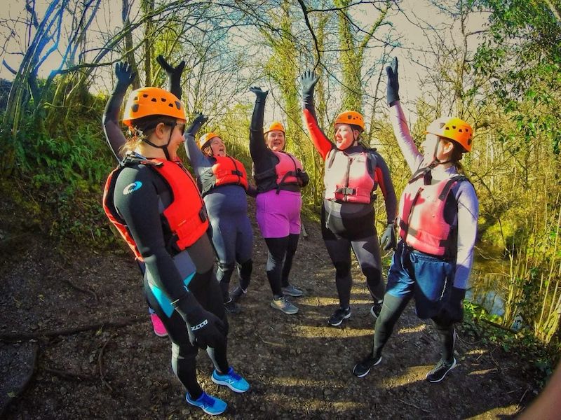 Five women raising hands in the midst of their gorge walking adventure