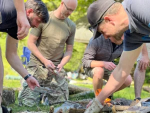 Group of men making fire in their wild camping stag do adventure in Cardiff