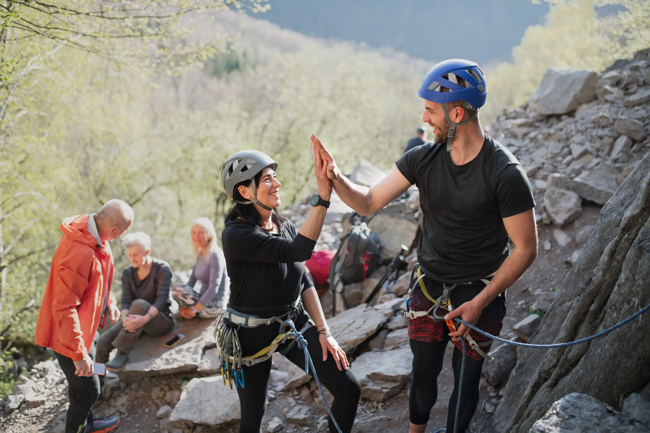 A man and a woman are giving each other a high-five on top of the mountain during their team building activity