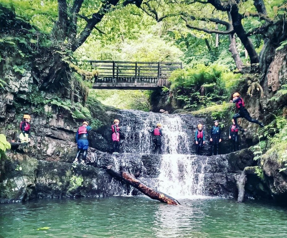 Group of people in the midst of a waterfall enjoying their gorge walking adventure