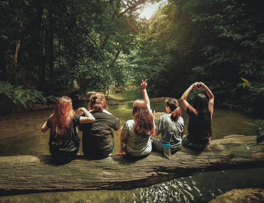 Five women sitting by the river posing with their backs turned during the hen do hiking adventure