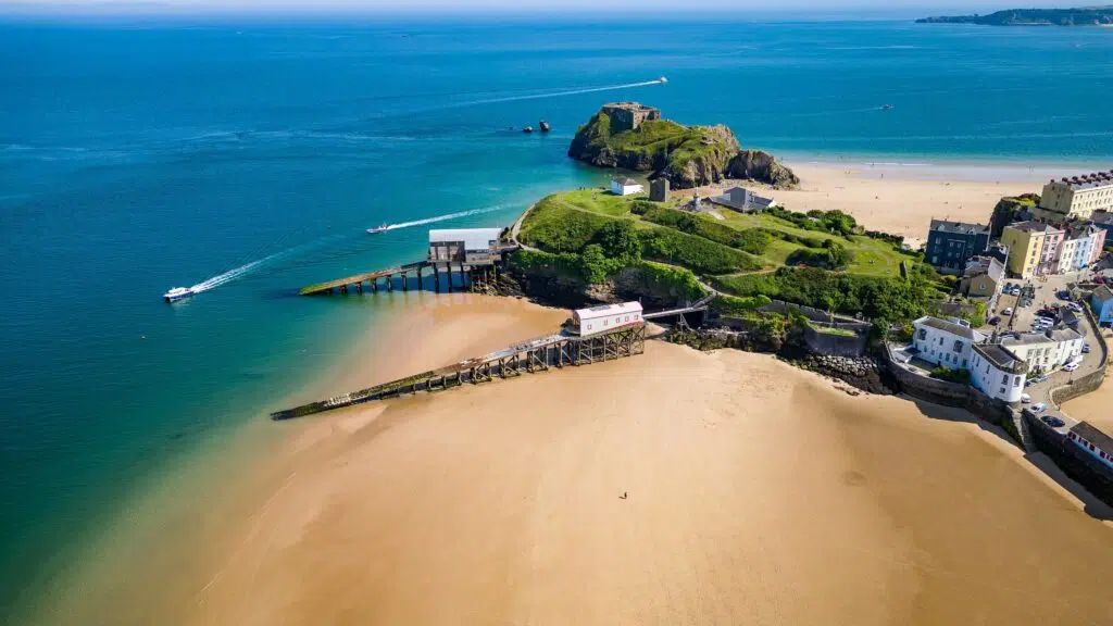 Beautiful aerial drone view of a coast town with sandy beaches and colorful buildings in South Wales, UK