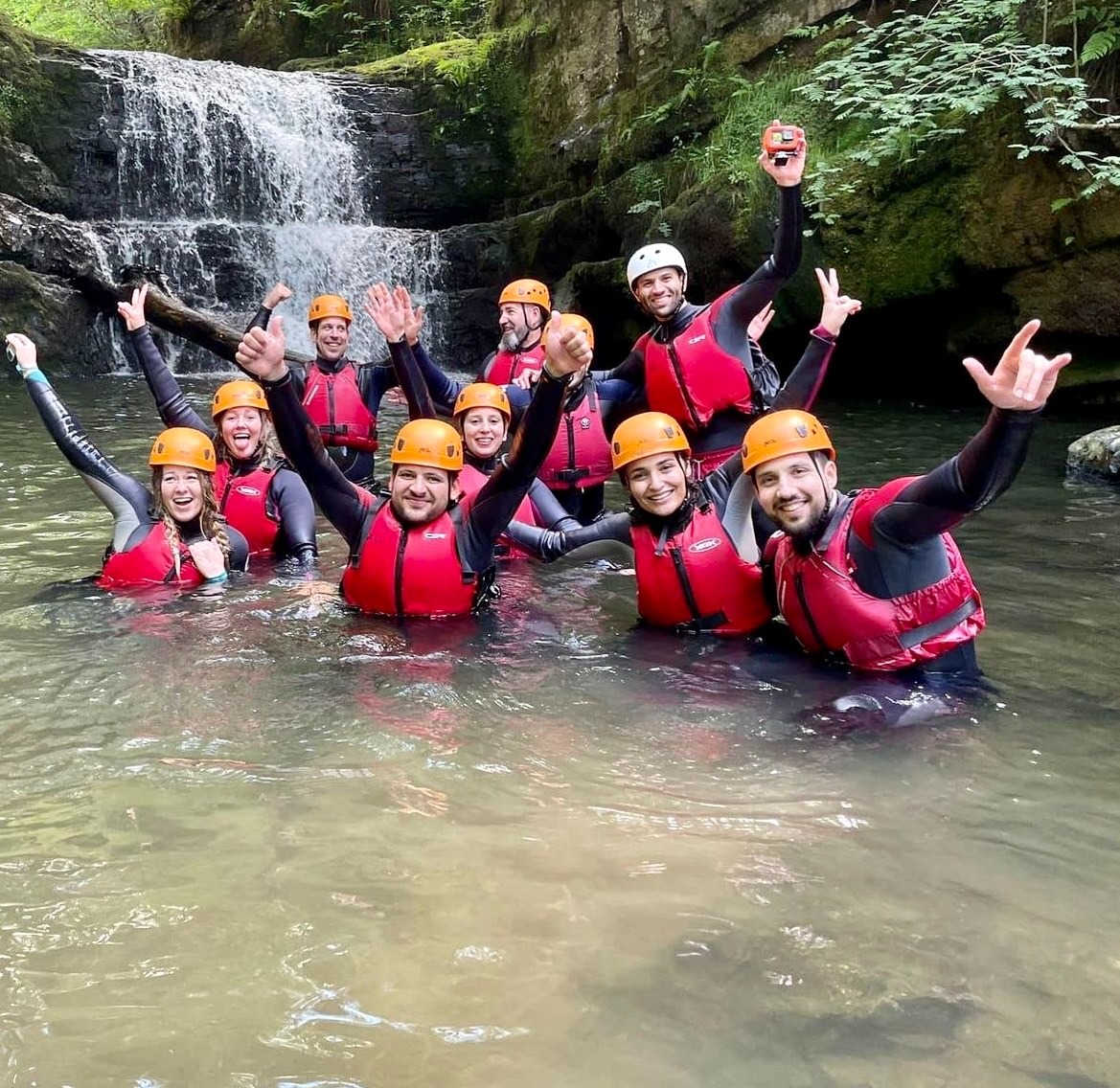 Group of individuals enjoying the waterfall and smiling on the camera