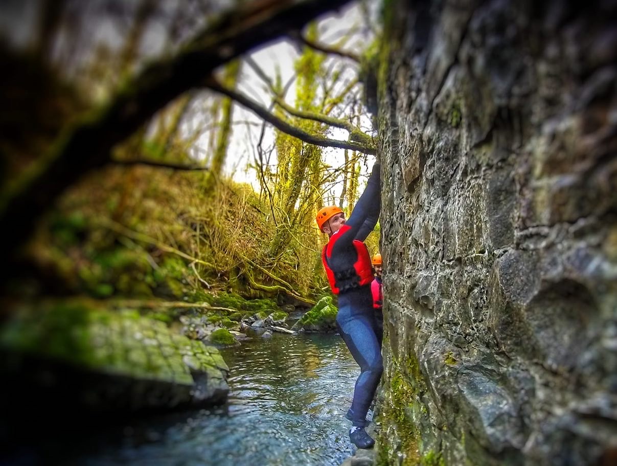 A person navigating a rocky river gorge in Wales