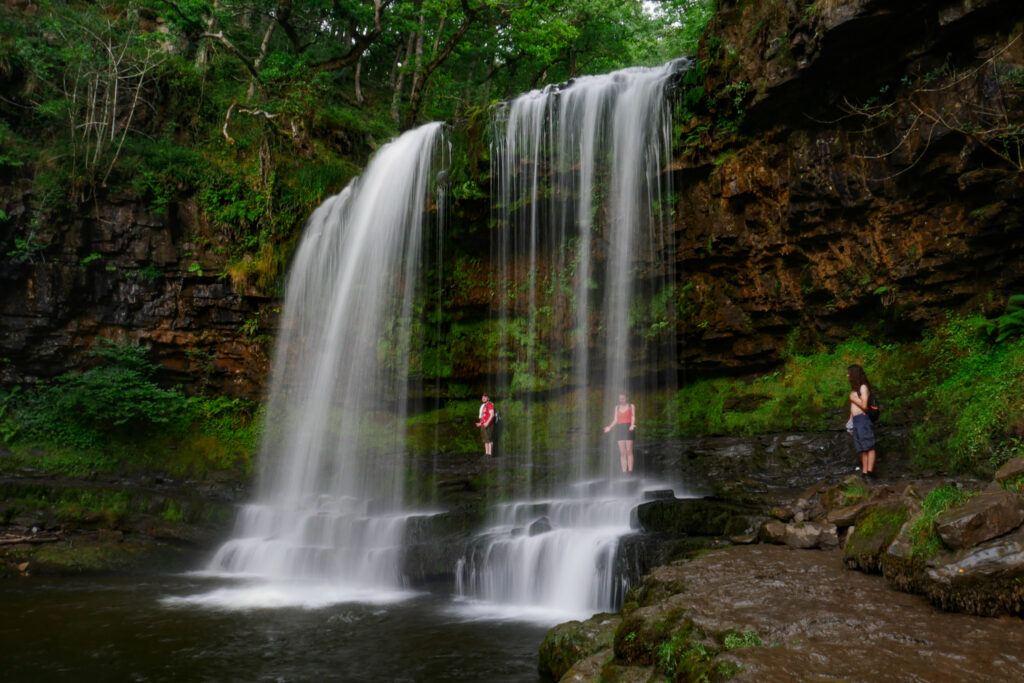 Three adventurers traversing a majestic waterfalls in the Brecon Beacons