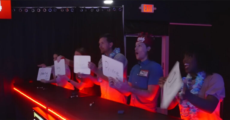 A team of game show contestant showing their answers on a white board