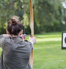 Back of a woman who is aiming her bow to the target