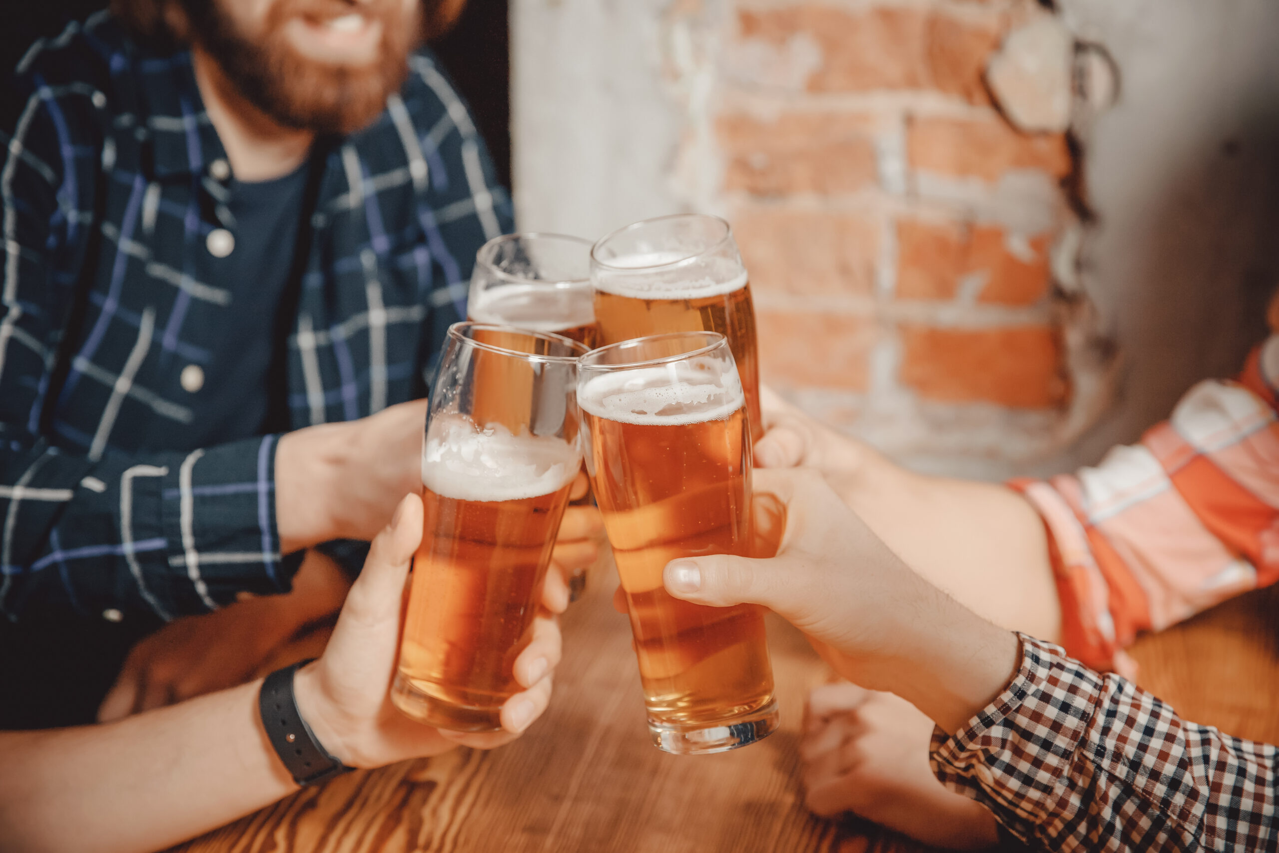 Four people clinking glasses of beer together during a stag do celebration.