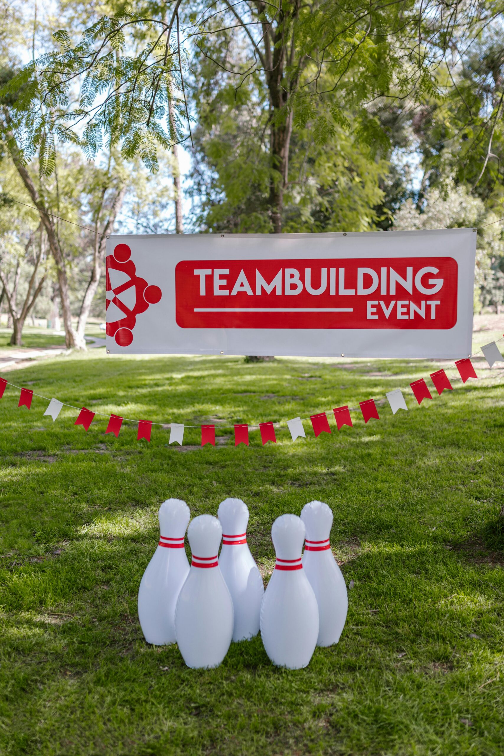 Team building event banner above a set of bowling pins on the grass