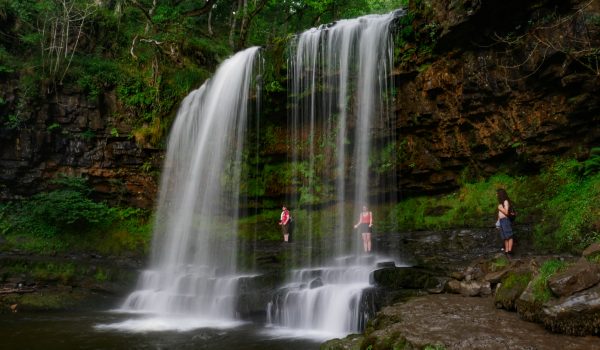 Three adventurers traversing a majestic waterfalls in the Brecon Beacons