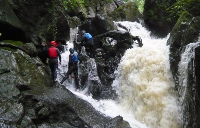 group of people walking up rocks and flowing water